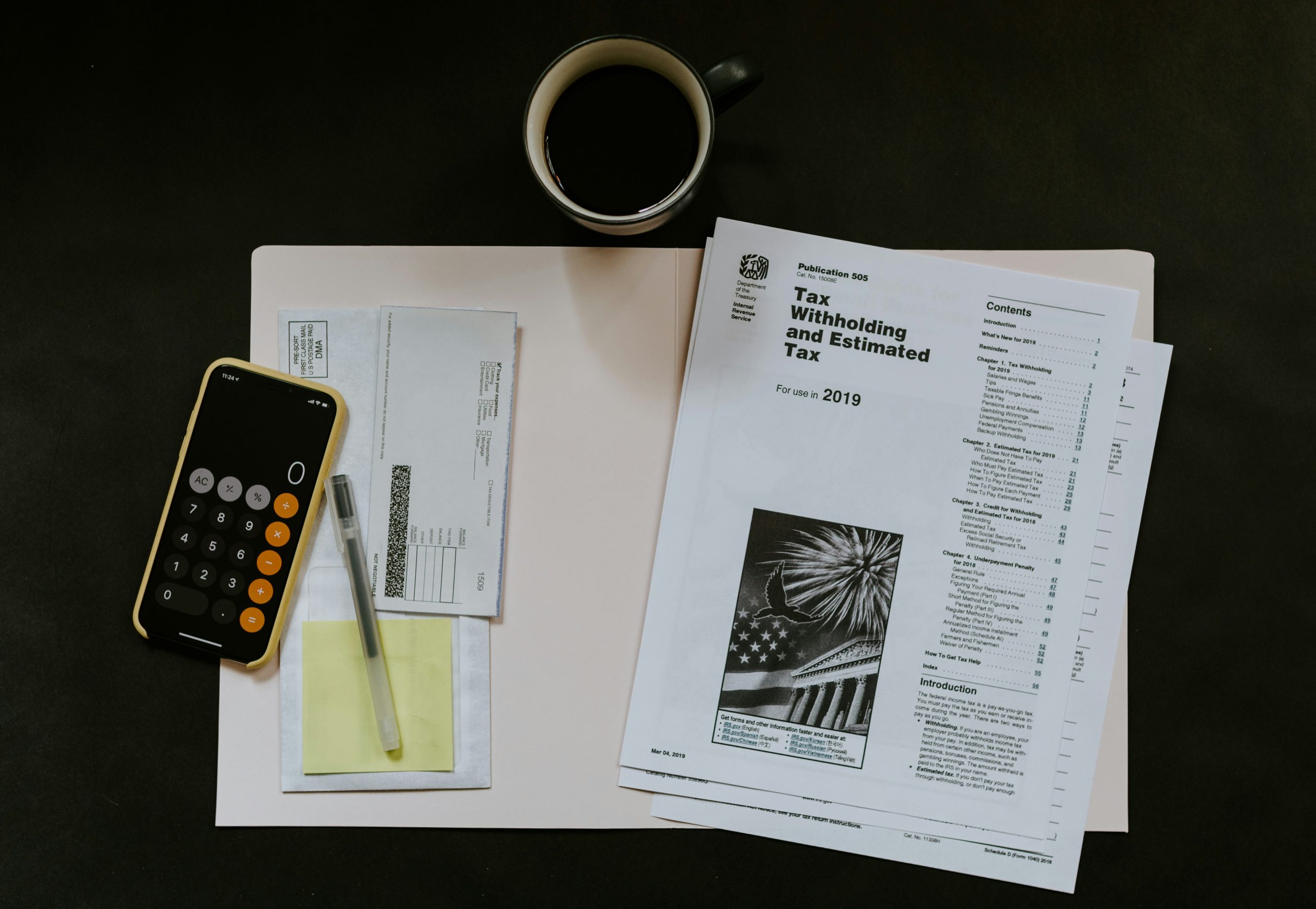 A table with a calculator, financial documents, and a coffee cup.