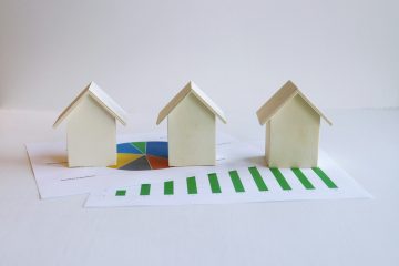 Paper models of houses with financial charts.