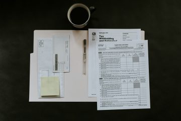 A desk with sales invoices, documents, and a coffee cup.