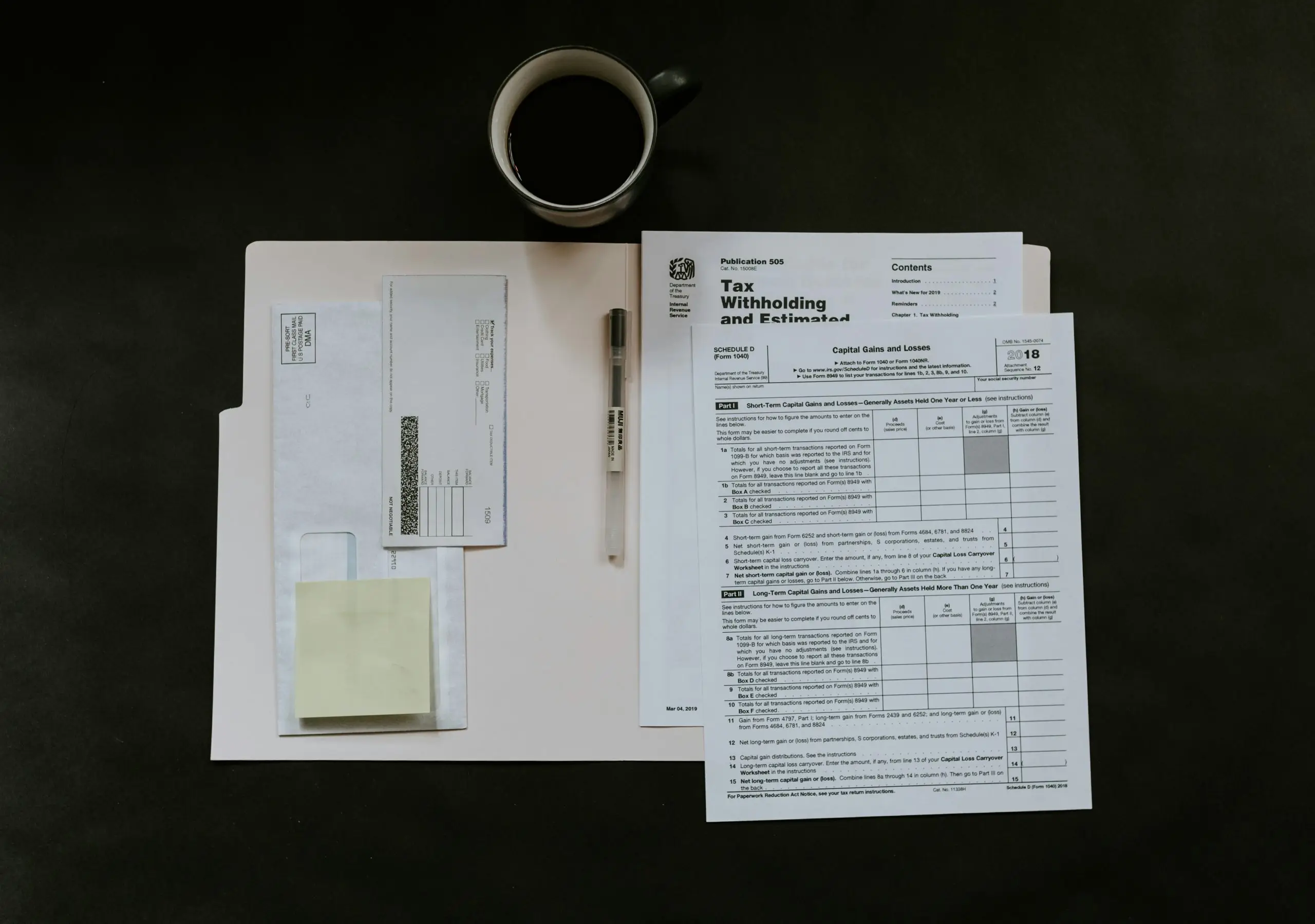 A desk with sales invoices, documents, and a coffee cup.