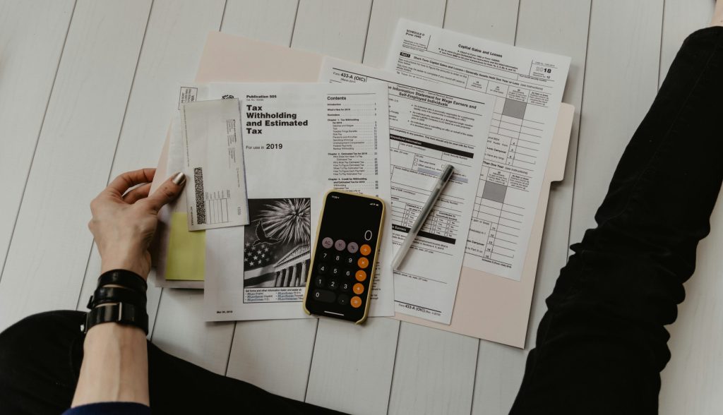 A person calculating withholding tax with a pen and calculator.